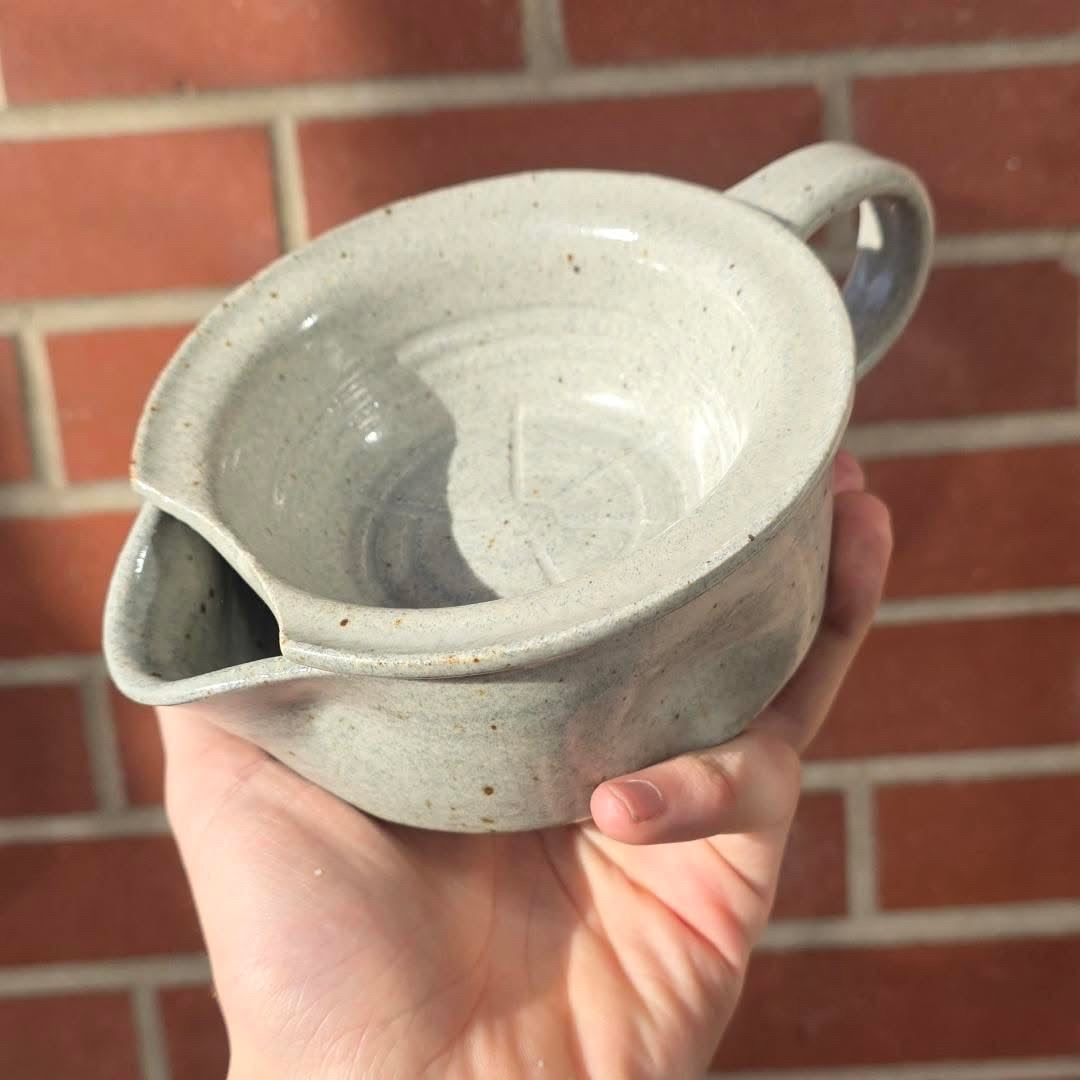 Lot. 15 Scuttle Style Shaving Bowl, a hand-thrown ceramic pouring bowl with handle and spout, held against a brick wall, ideal for a classic shaving experience.