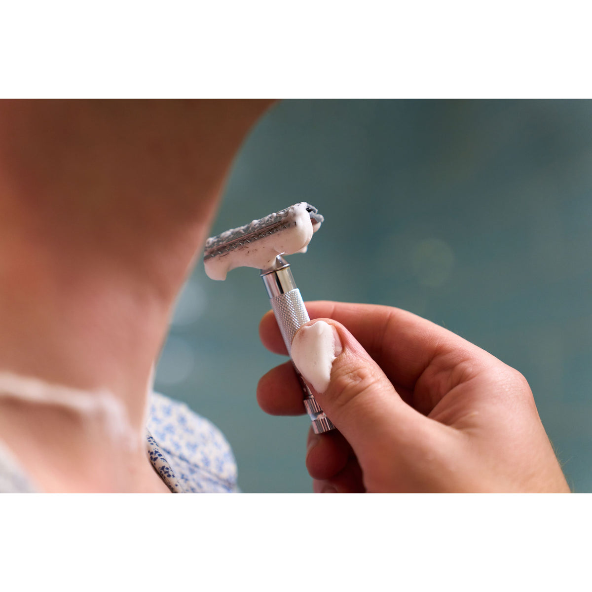 A close-up of a person shaving their neck with the sleek Merkur 34C DE Safety Razor, applying shaving cream to their skin.