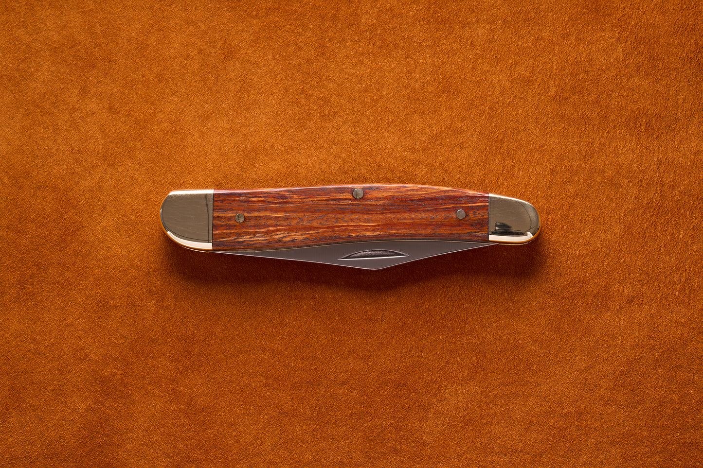 Grohmann Pocket Knife with Silver and Rosewood Handle, 4, on leather surface, showcasing its polished metal bolsters and stained wood grain.