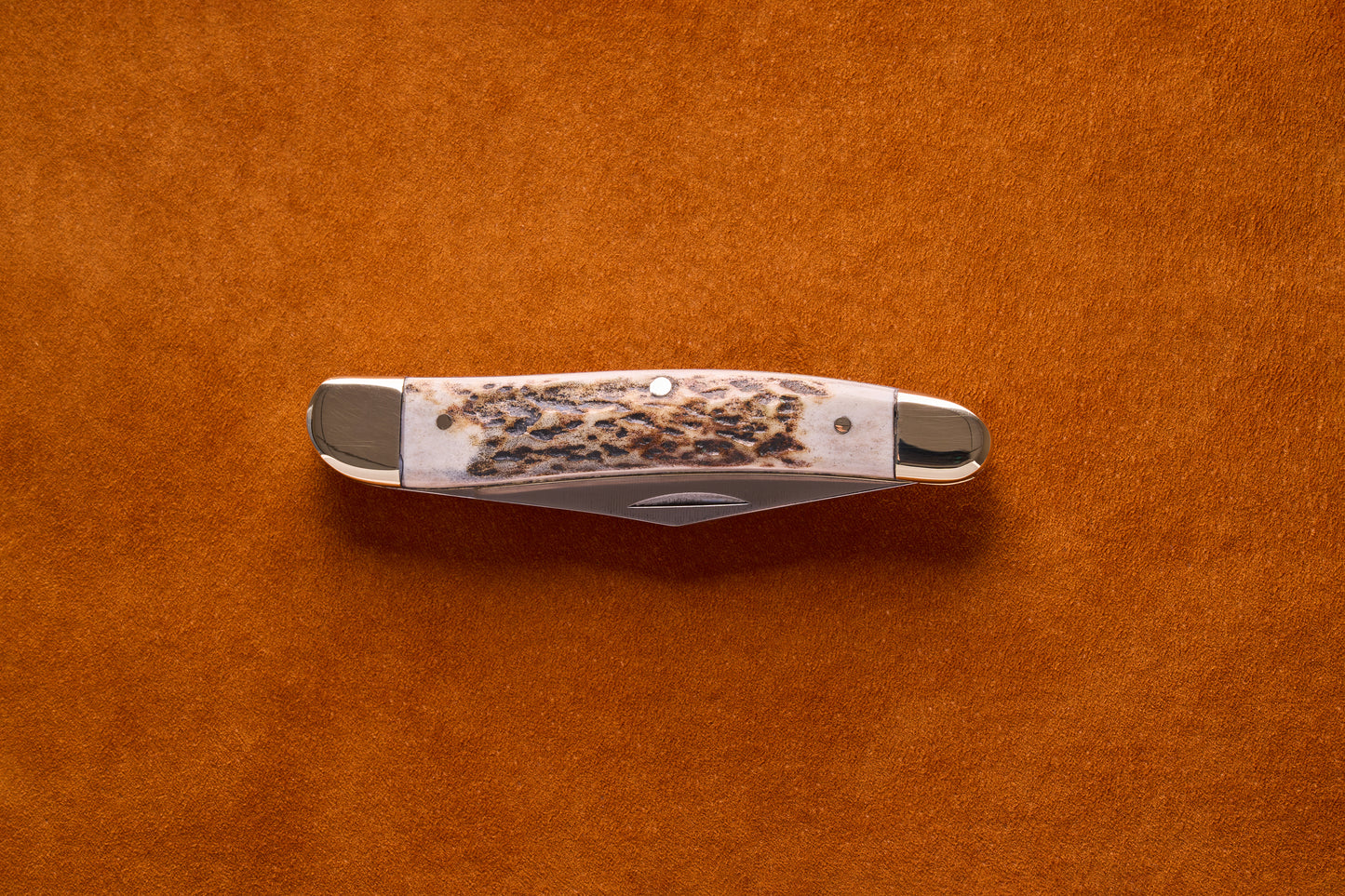 Grohmann Pocket Knife with Silver and Staghorn Handle, 4, resting on suede, showcasing its folded blade and polished bolsters, epitomizing timeless craftsmanship.