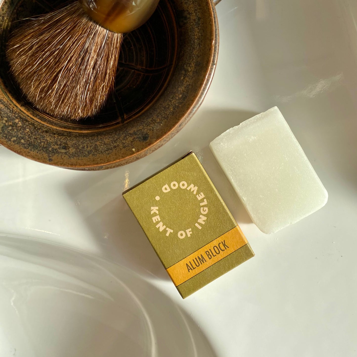 Kent of Inglewood Potassium Alum Block on a bathroom counter, alongside its box and a shaving brush, ideal for soothing post-shave nicks and irritation.