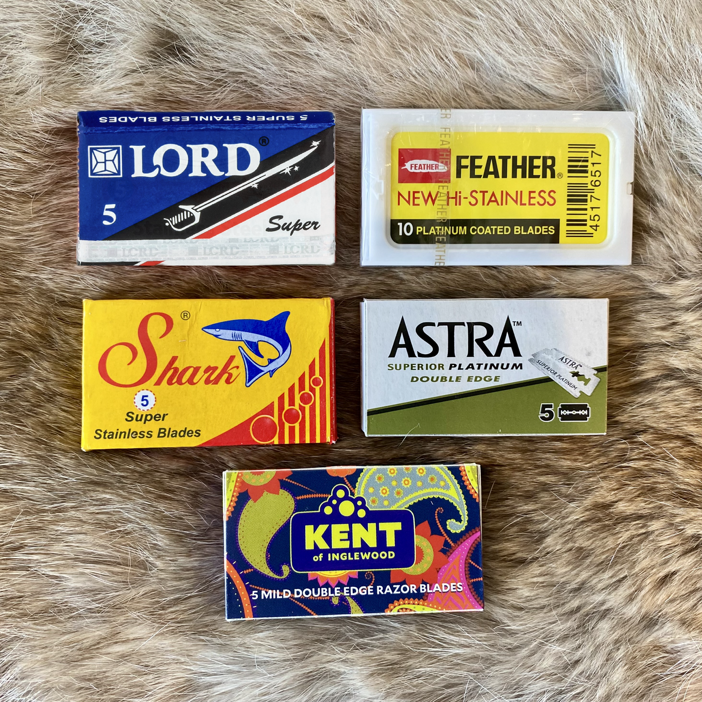Five packages of razor blades from Lord, Feather, Astra, Shark, and Kent on a fur surface.