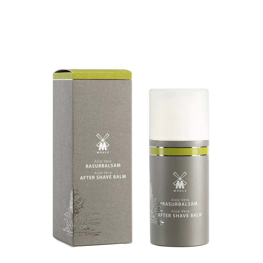 A bottle of Mühle Aloe Vera Aftershave Balm stands beside its matching gray and green box, which features minimalist text and botanical illustrations—ideal for soothing sensitive skin after shaving.