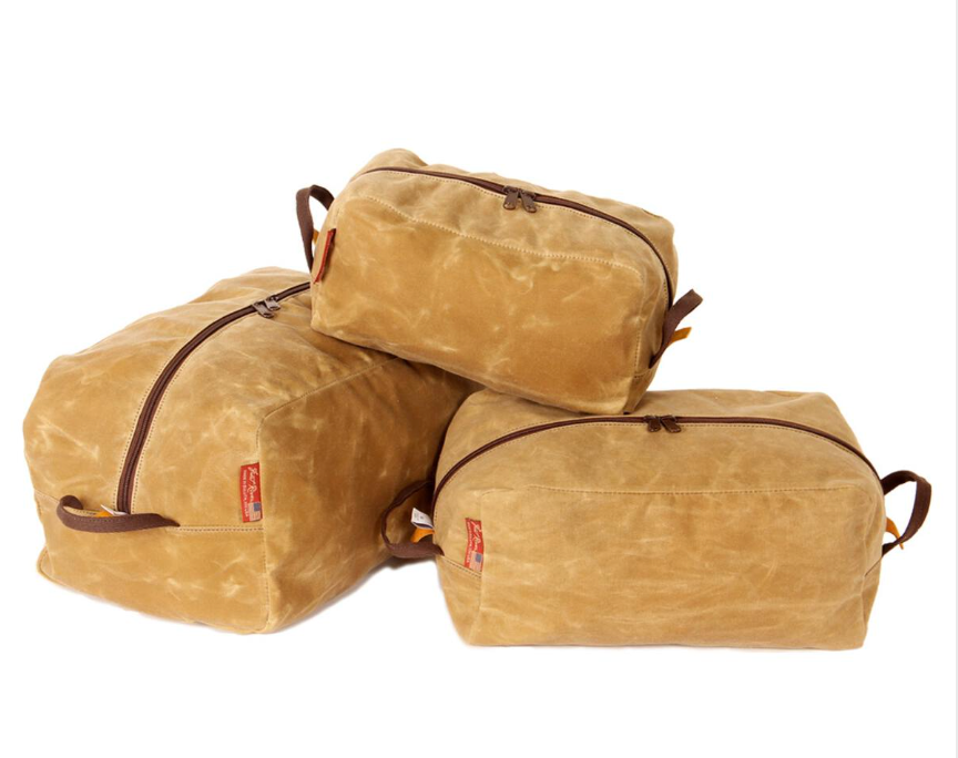 Three tan Frost River Iona’s Pack Cubes of varying sizes, each featuring brown zippers and small red tags, are arranged against a white background—showcasing the handcrafted reliability you expect from Frost River gear.