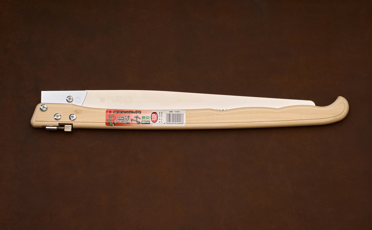 A Gyokucho Megumi Folding Saw 330mm with a long metal blade and a light-colored wooden handle, shown in the closed position.