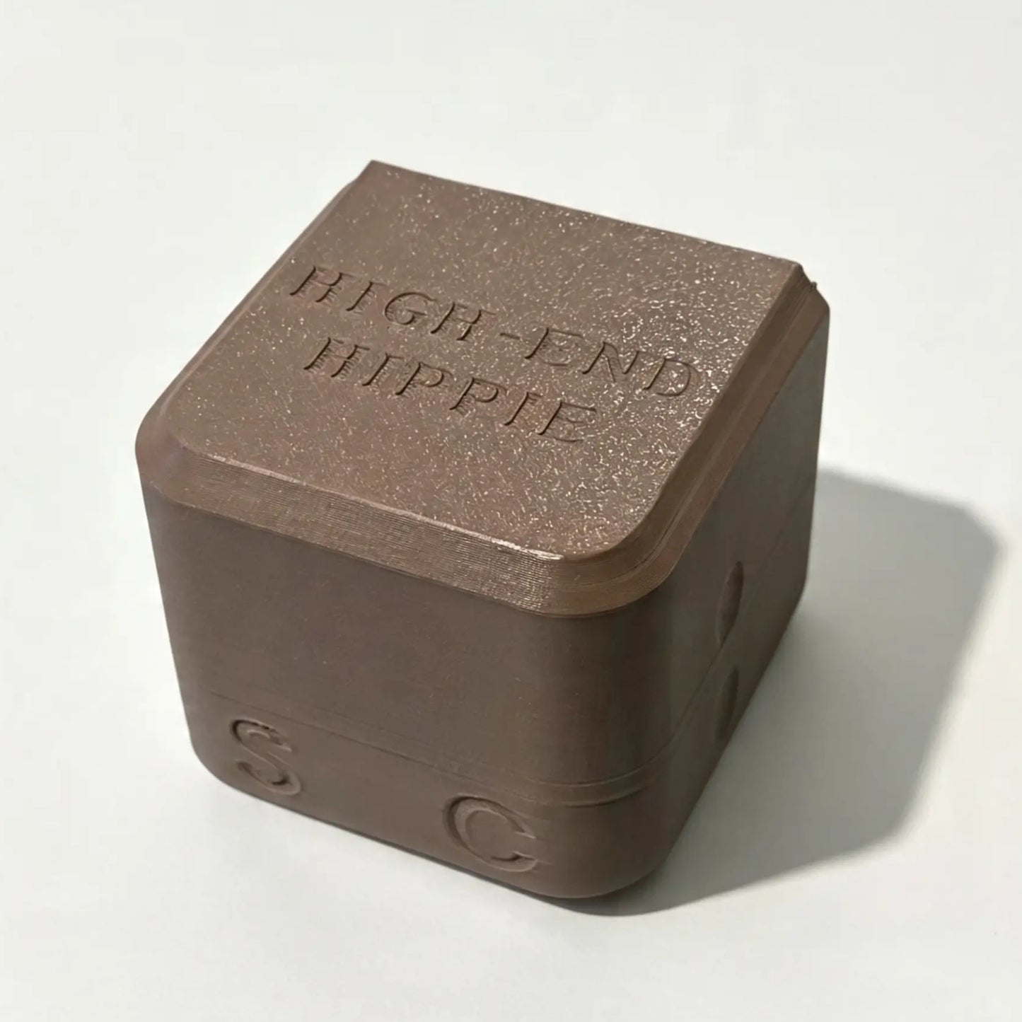 A brown, cube-shaped case with “HIGH END HIPPIE” engraved on the top and the letters S and C on its sides, designed specifically for The High End Hippie 2-in-1 Shampoo and Conditioner—perfect for sustainable shower storage, shown resting on a plain white surface.