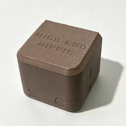 A brown, cube-shaped case with “HIGH END HIPPIE” engraved on the top and the letters S and C on its sides, designed specifically for The High End Hippie 2-in-1 Shampoo and Conditioner—perfect for sustainable shower storage, shown resting on a plain white surface.