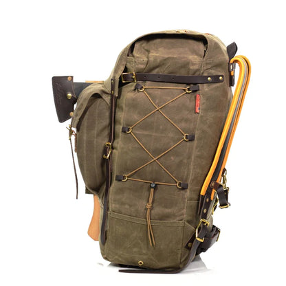 Frost River Isle Royale Pack, a rugged waxed-canvas backpack with leather straps, external lacing, hatchet, and shovel, designed for camping and backcountry adventures.