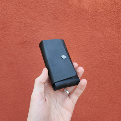 Hand holding Jack Raymond Leather Safety Razor Holster, a sleek black pouch with a metal snap closure, embodying classic shaving elegance.