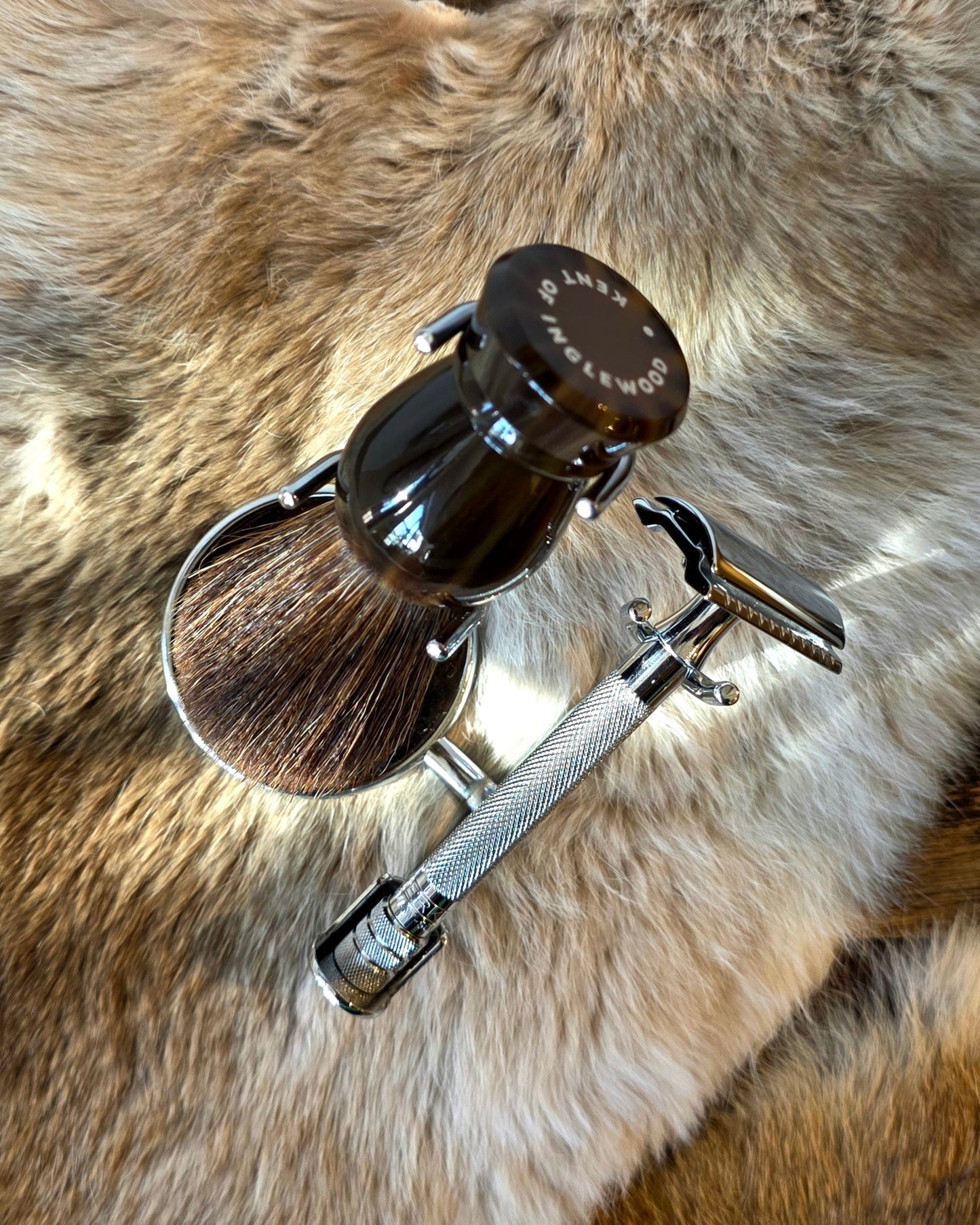 Kent's Better Shaving Kit features a badger-hair brush in a stand and a knurled-handle safety razor on a faux-fur surface.
