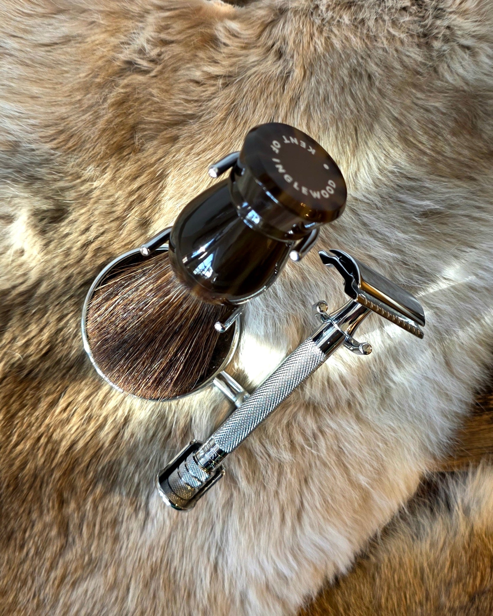 Kent's Better Shaving Kit features a badger-hair brush in a stand and a knurled-handle safety razor on a faux-fur surface.