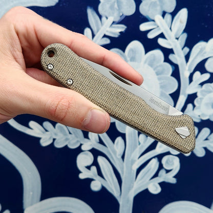 Hand holding the Kershaw Federalist folding pocket knife with a Micarta handle, showcasing its classic slipjoint design ideal for hardworking individuals.