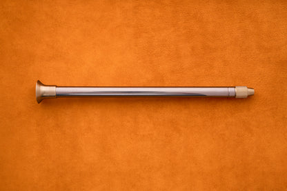 The Barebones Telescoping Fire Blower rests horizontally on an orange suede surface, evoking the must-have tools you’d bring along for an outdoor adventure.