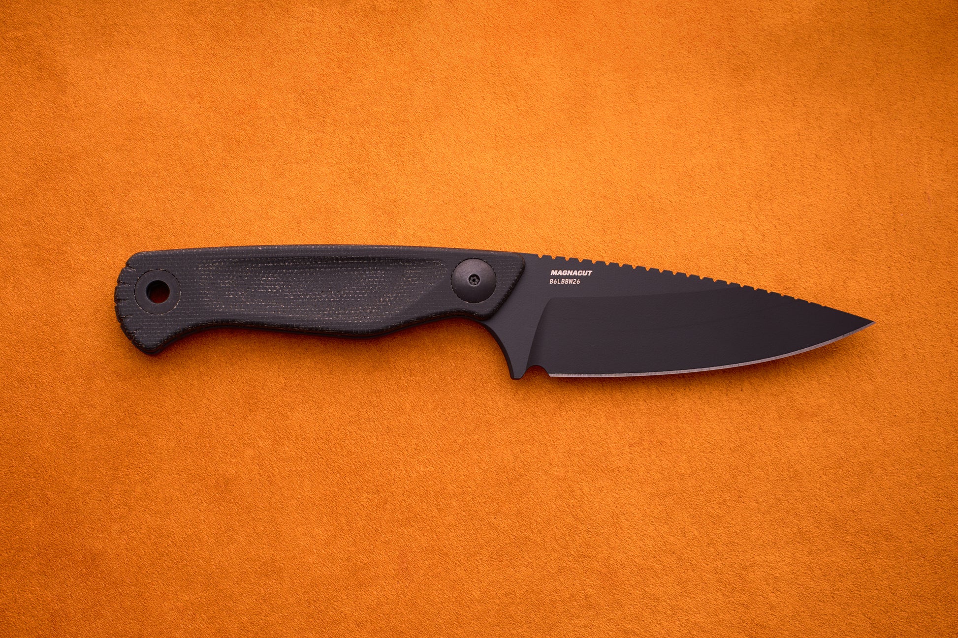 A Benchmade Dacian - Black Micarta compact fixed-blade knife with a serrated edge and premium CPM-Magnacut steel is displayed on an orange textured background.