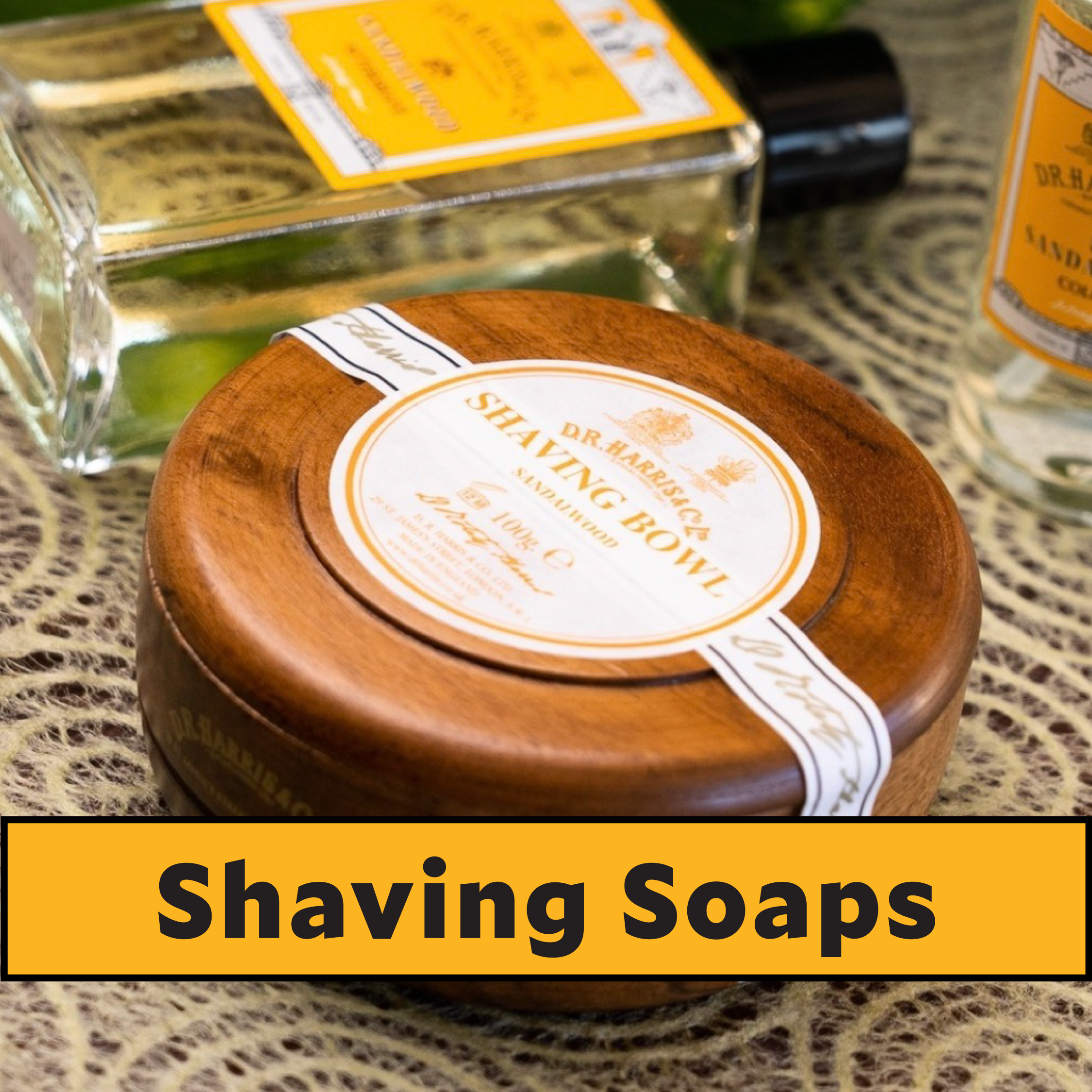 Wooden shaving bowl with a label and bottles in the background on a textured surface.