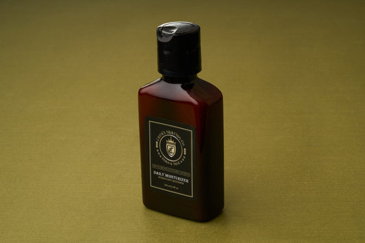 A dark brown plastic bottle with a black cap, labeled Crown Shaving Co. Daily Face Moisturizer, stands on an olive green surface. This daily face moisturizer is specially formulated without sulfates or parabens, making it ideal for use in harsh Canadian climates.