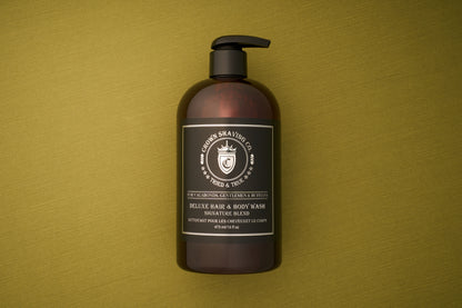 A brown pump bottle labeled Crown Shaving Co. Hair and Body Wash - Signature Scent 473mL/16oz rests on an olive green textured surface. The black label with white text features a crown logo and notes that this men’s body wash is sulfate and paraben free, offering a gentle yet effective cleanse.