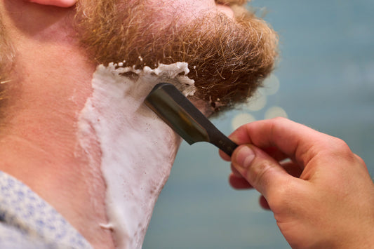 A close-up of a person’s neck being shaved with the Takami Kamisori Japanese Straight Razor Western Grind, with shaving cream applied under the beard, highlighting the precision and effortless glide of this shave-ready tool.