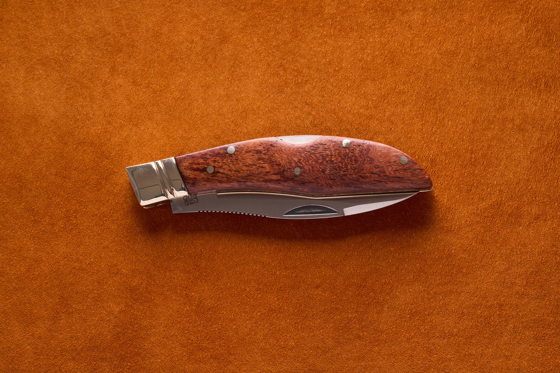 Grohmann Mini Russell Lockblade, 4, with a rosewood handle and stainless steel blade, resting on a suede surface.