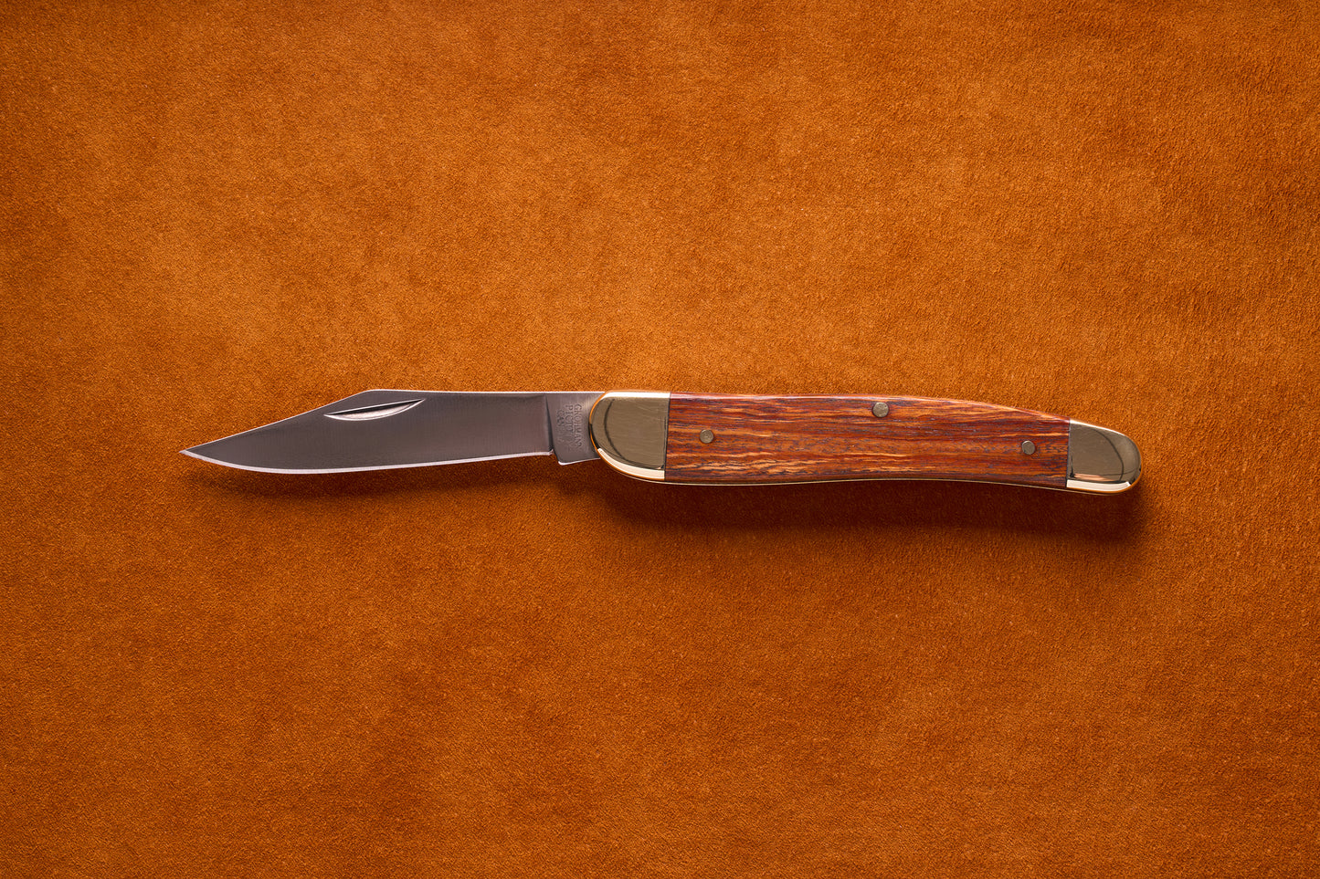 Grohmann Pocket Knife with Silver and Rosewood Handle, 4, featuring a stainless steel blade and brass bolsters, laid open on a textured background.