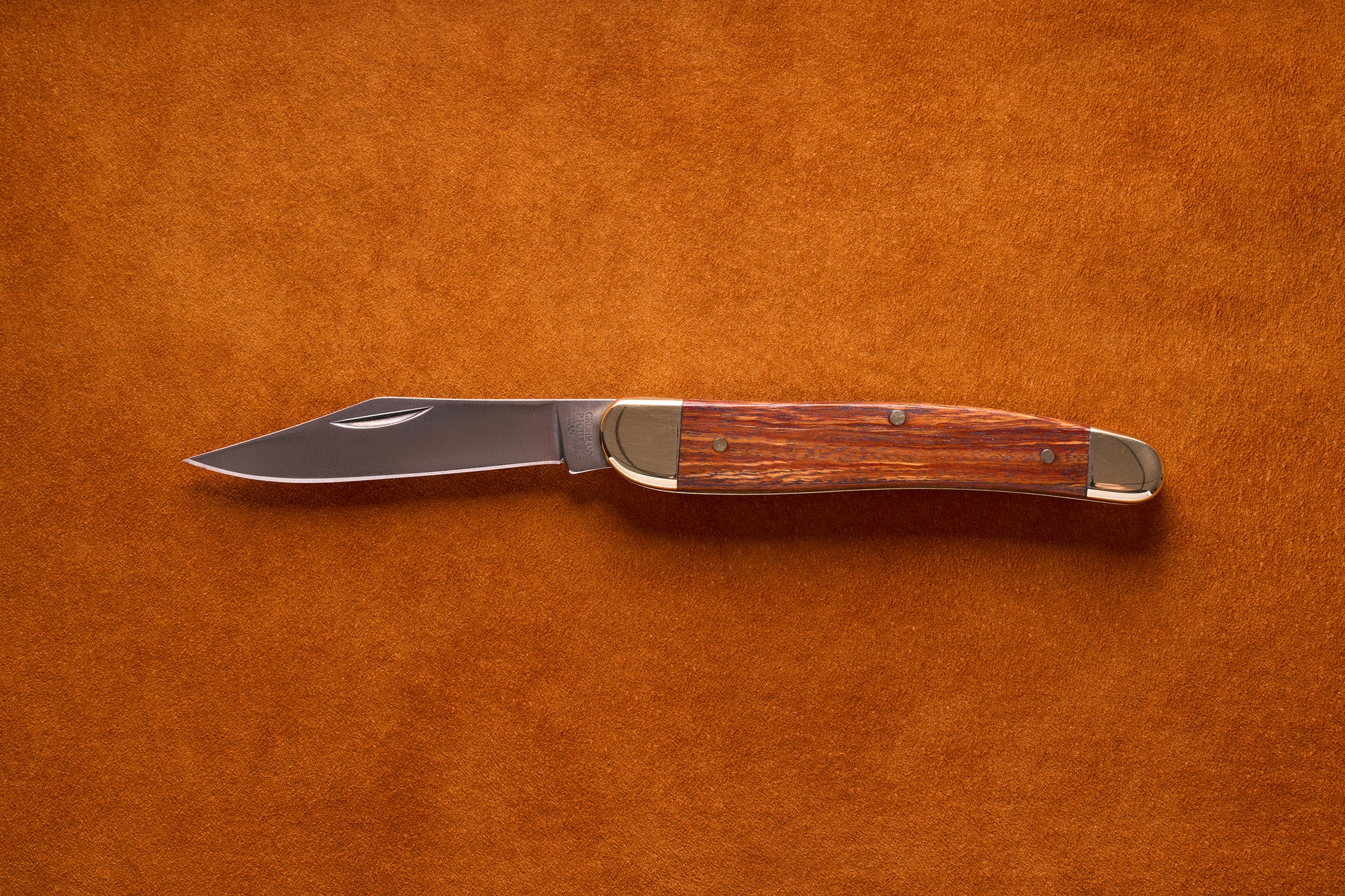 Grohmann Pocket Knife with Silver and Rosewood Handle, 4, featuring a stainless steel blade and brass bolsters, laid open on a textured background.