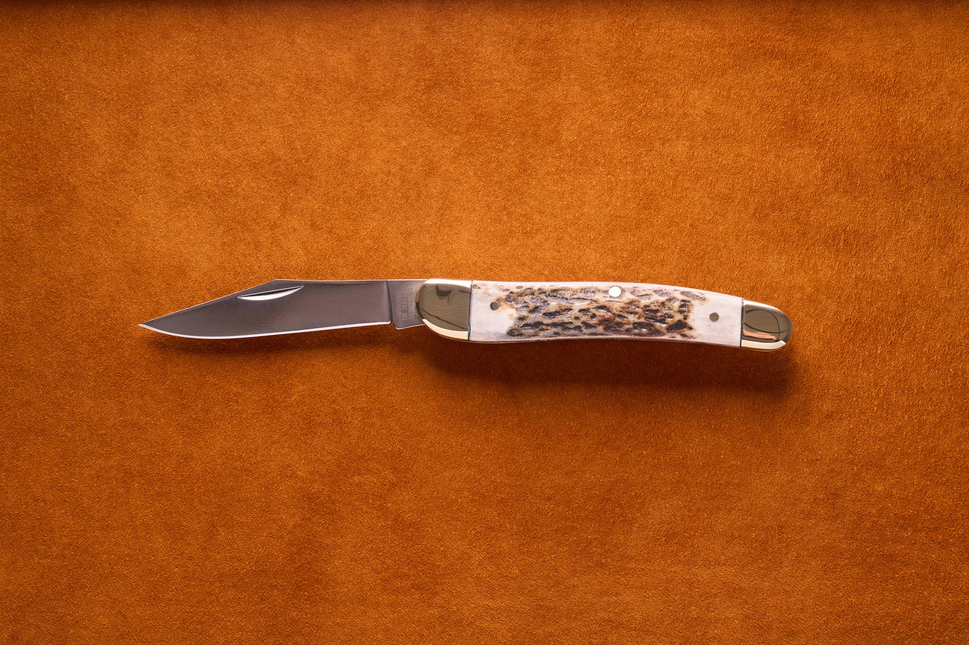 Grohmann Pocket Knife with Silver and Staghorn Handle, 4, featuring a stainless steel blade and brass bolsters, displayed on a suede surface.