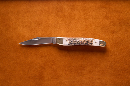 Grohmann Pocket Knife with Silver and Staghorn Handle, 4, featuring a stainless steel blade and brass bolsters, displayed on a suede surface.