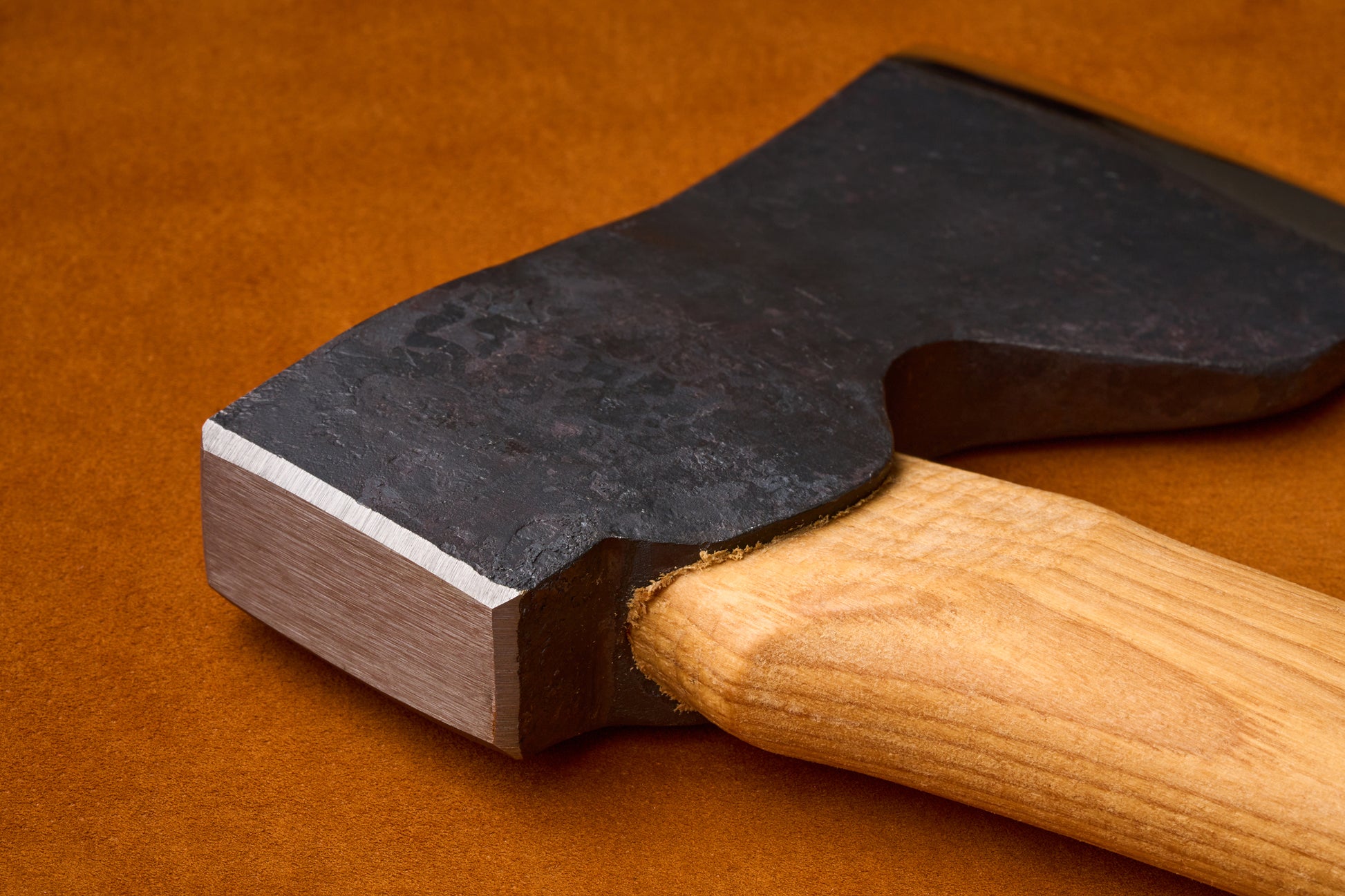 Close-up of a axe with a wooden handle on an orange background