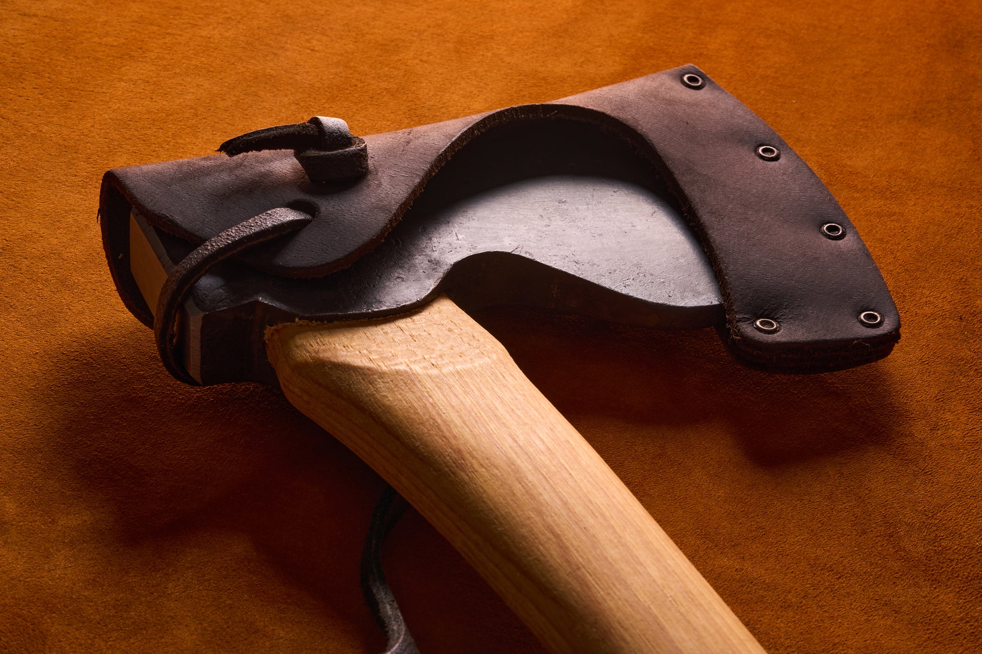 Wooden axe with a leather sheath on an orange background