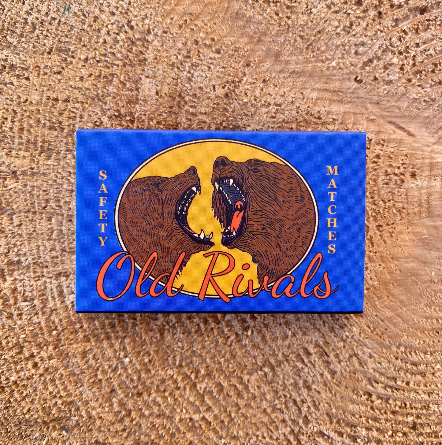 Matches box with bear illustration and 'Old Rivals' branding on a wooden surface