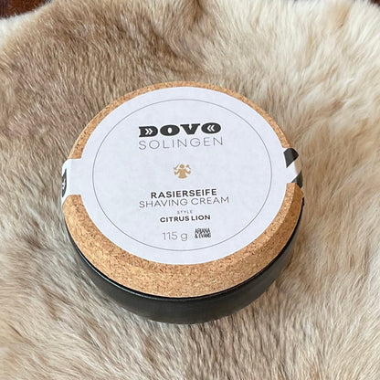 Dovo Citrus Lion Shaving Soap in a cork-lidded stoneware bowl, 115g, on a fur surface, highlighting its citrus and cedar scent blend.