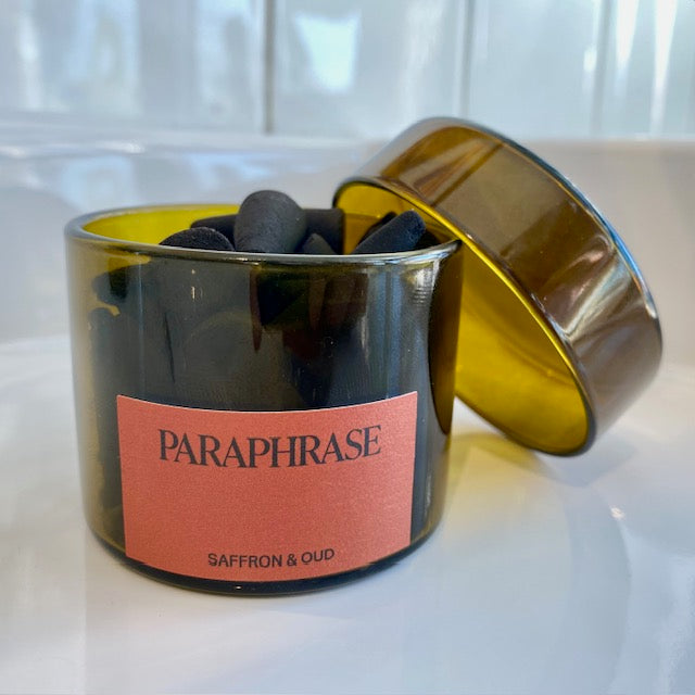 Paraphrase Incense Cones in an amber glass jar evoke ancient fragrances of saffron and oud, offering a modern sensory exploration by Paraphrase Fragrance.