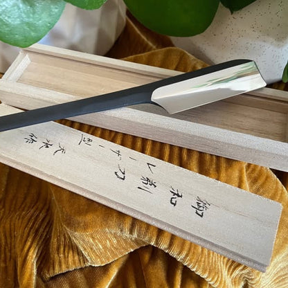 Takami Kamisori Japanese Straight Razor with Western Grind, featuring a black handle and polished blade, rests on a wooden box with Japanese characters.