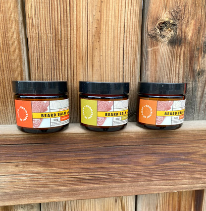 Kent of Inglewood Citrus Beard Balm jars on a rustic fence, showcasing light hold and moisture benefits for beards, embodying the brand's commitment to enjoyable grooming experiences.