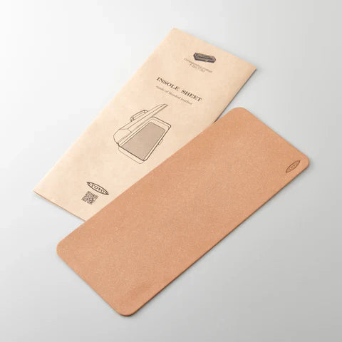 A Toyo 350 series Bonded Leather Insole Sheet rests next to its beige, Toyo Steel-inspired packaging featuring a shoe line drawing and product details, both neatly displayed on a light gray surface.