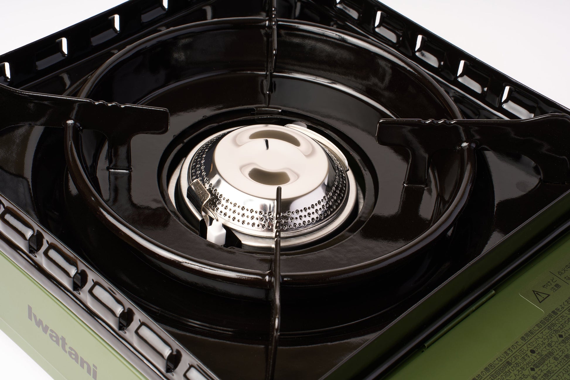 A close-up view of the Iwatani Cassette Konro "Tough Maru" Portable Stove, a butane-powered camping burner featuring black metal grates and a silver burner head on a green base, photographed against a white background.