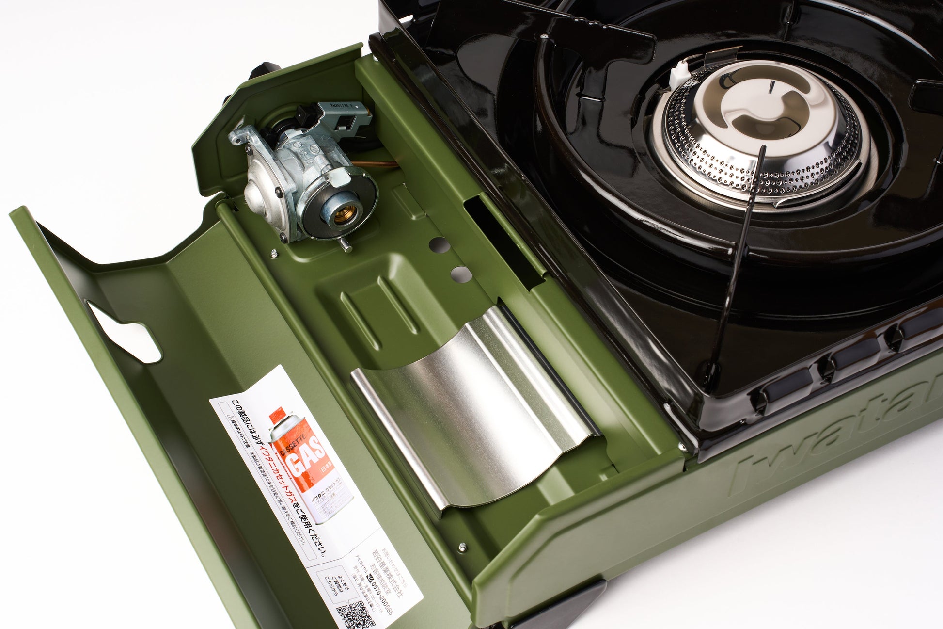 A close-up of an Iwatani Cassette Konro "Tough Maru" Portable Stove in green with its lid open, displaying the burner, gas cartridge compartment, and a label featuring usage instructions.