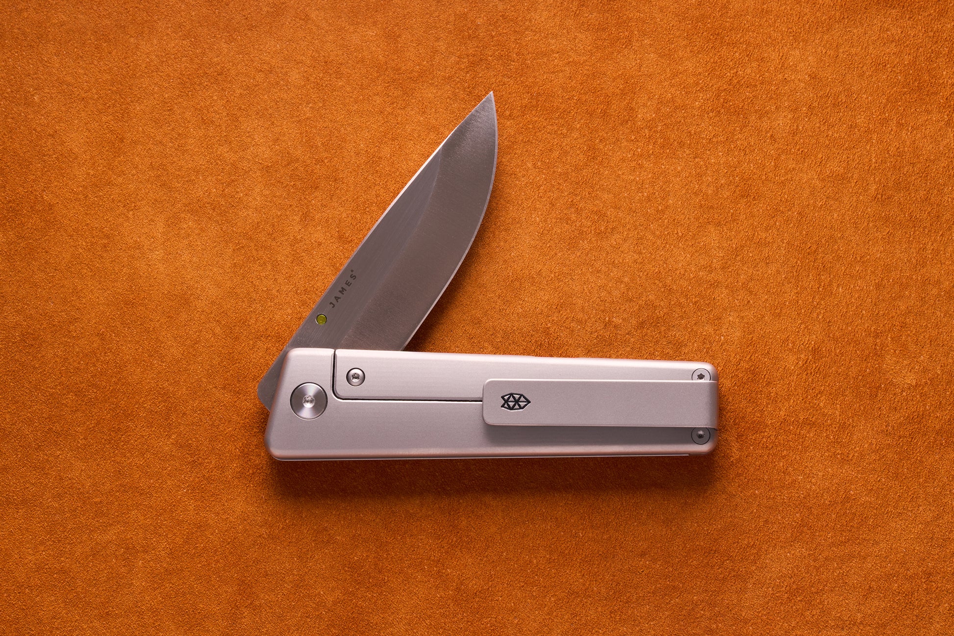 James Chapter 2 knife with sleek silver handle and diamond logo, partly opened, showcasing its titanium frame-lock and stamped S35vn blade.