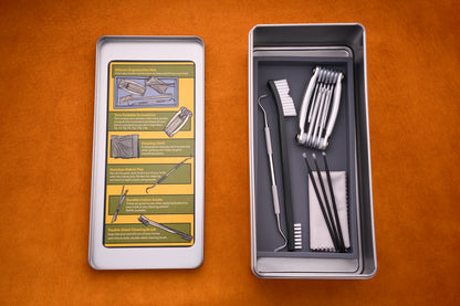 The Kent of Inglewood Pocket Knife Care Kit is shown in a metal box containing cleaning tools, brushes, tweezers, detailing swabs, and a cloth on the right side; the inside of the left lid features illustrated instructions for using the kit—all set against an orange background.