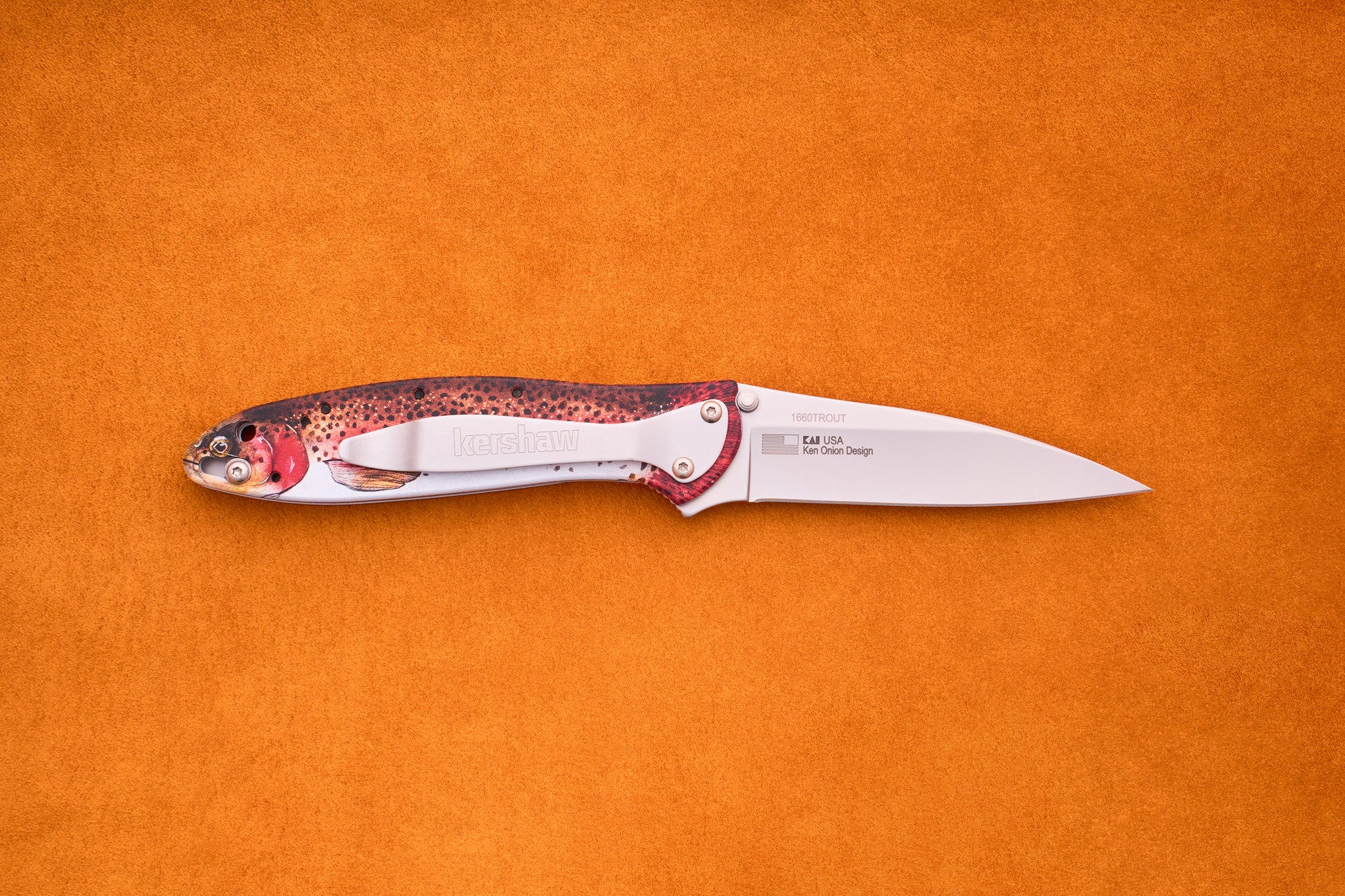 The Kershaw Leek Rainbow Trout is a folding pocket knife featuring a silver blade and a handle adorned with a vibrant ladybug pattern, shown against an orange textured background—an ideal EDC knife for everyday carry enthusiasts who appreciate both style and practicality.