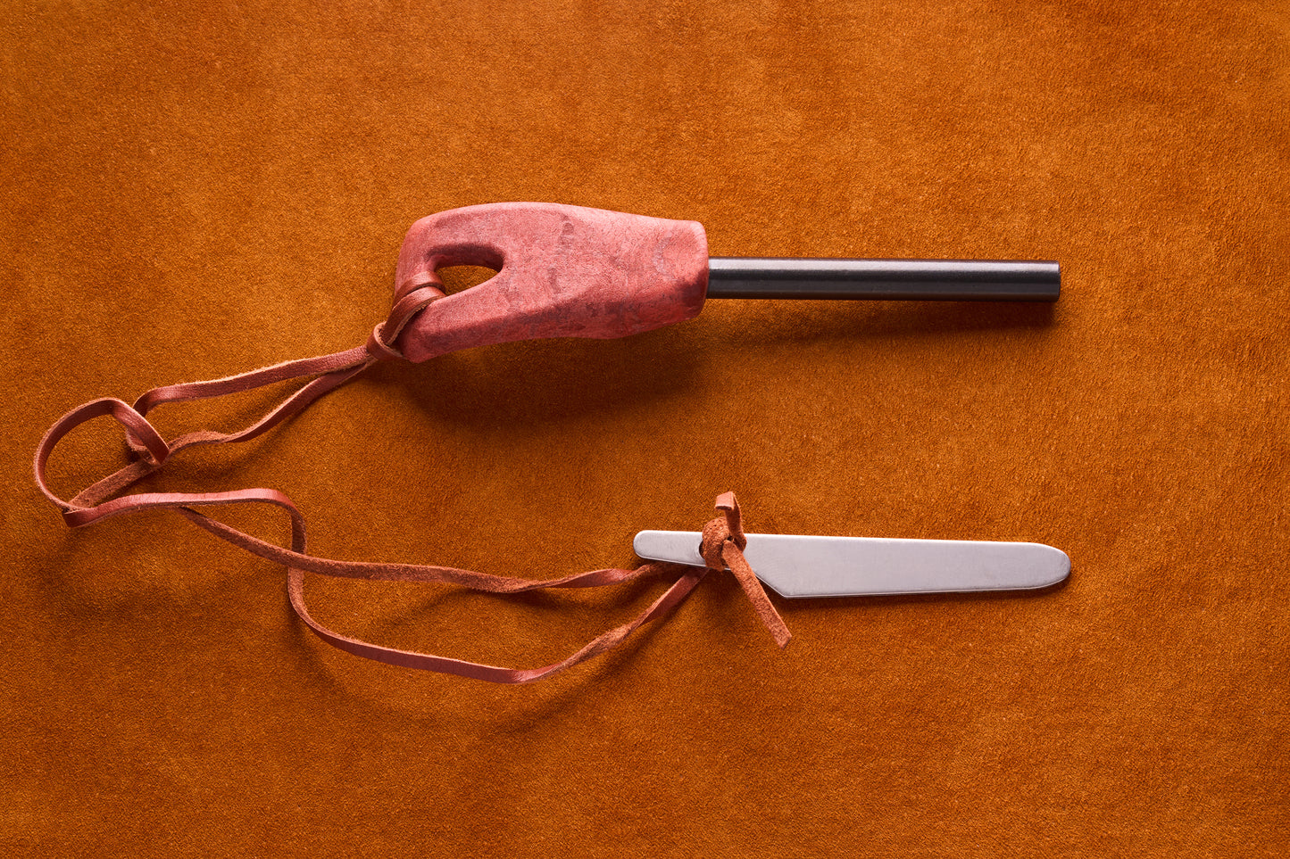 Kupilka Firesteel with contoured handle and metal striker, ideal for campers to generate sparks. Displayed on a textured surface, this tool embodies Kent of Inglewood's adventurous spirit.