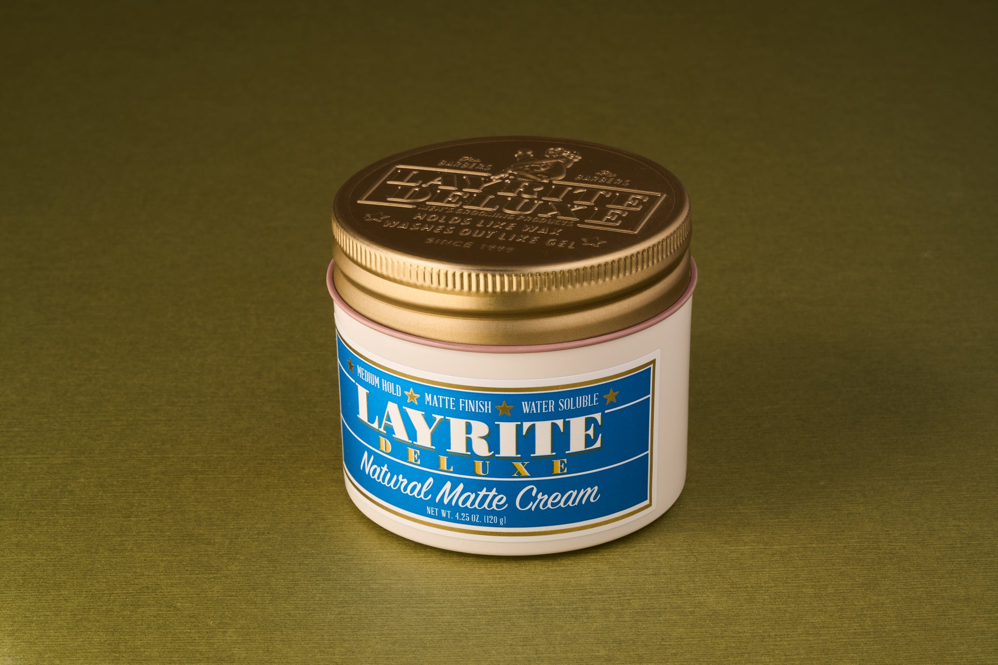 Layrite Natural Matte Cream jar with gold lid and blue label, offers medium hold and matte finish for natural hairstyles. Ideal for casual looks, water-soluble.