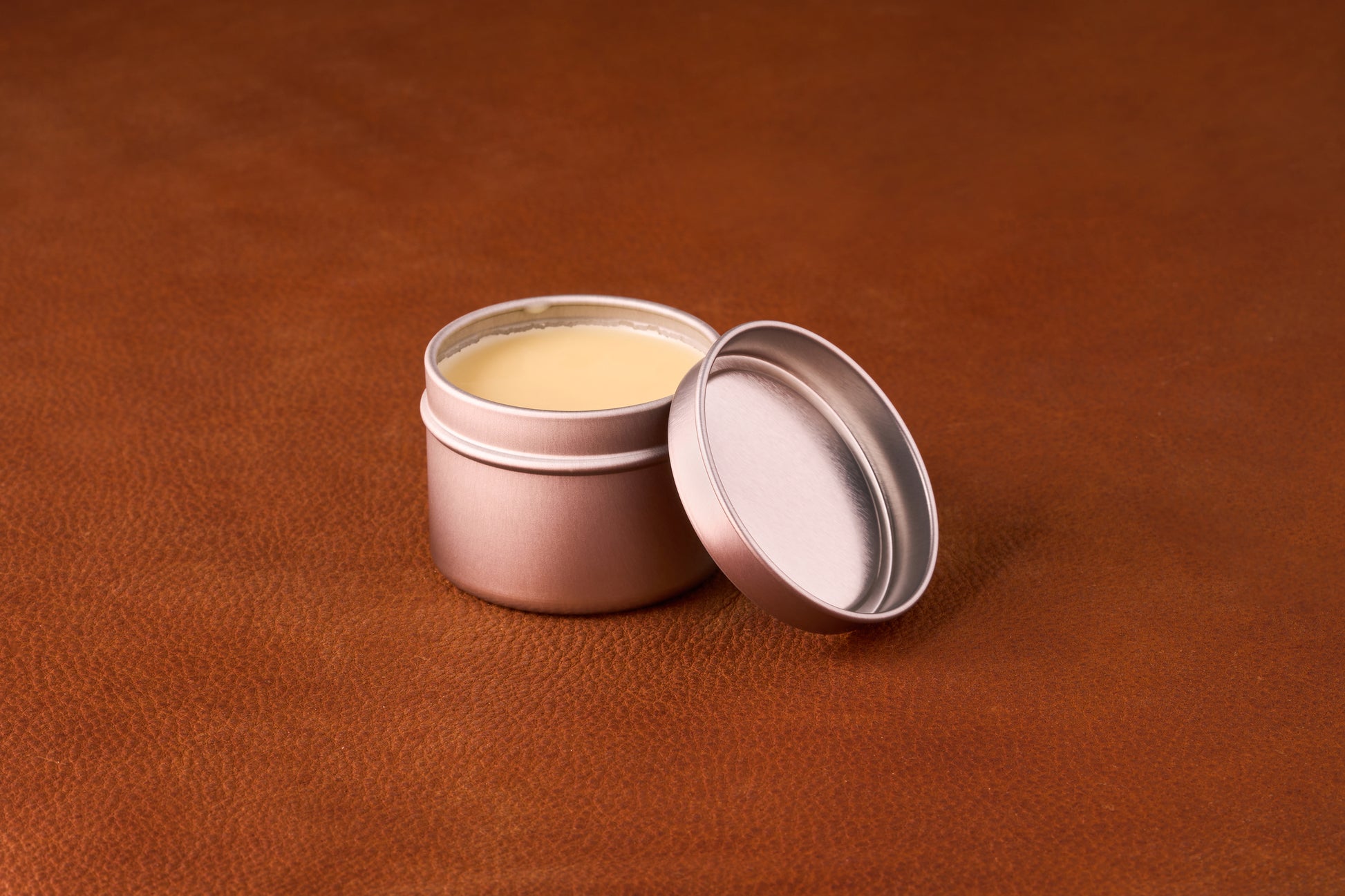 Mammoth Beard Co. Beard Balm Highland Ember 60ml in an open metal tin on leather, showcasing its solid, pale yellow balm ideal for moisturizing and taming unruly beards.