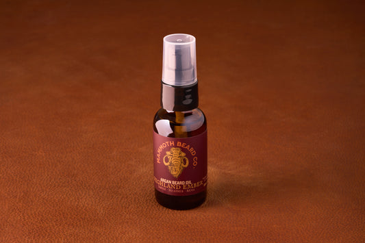 Mammoth Beard Co. Beard Oil - Highland Ember 30ml bottle on leather surface, featuring smoke, heather, and moss scent accents, ideal for a regal beard grooming experience.