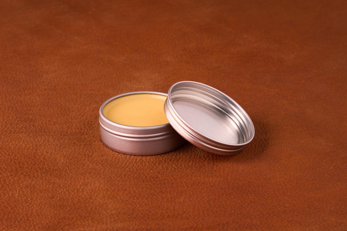Mammoth Beard Co. Sex & Cigars Moustache Wax 1oz, in an open tin, displayed on a leather surface, highlighting its smooth texture ideal for versatile styling.