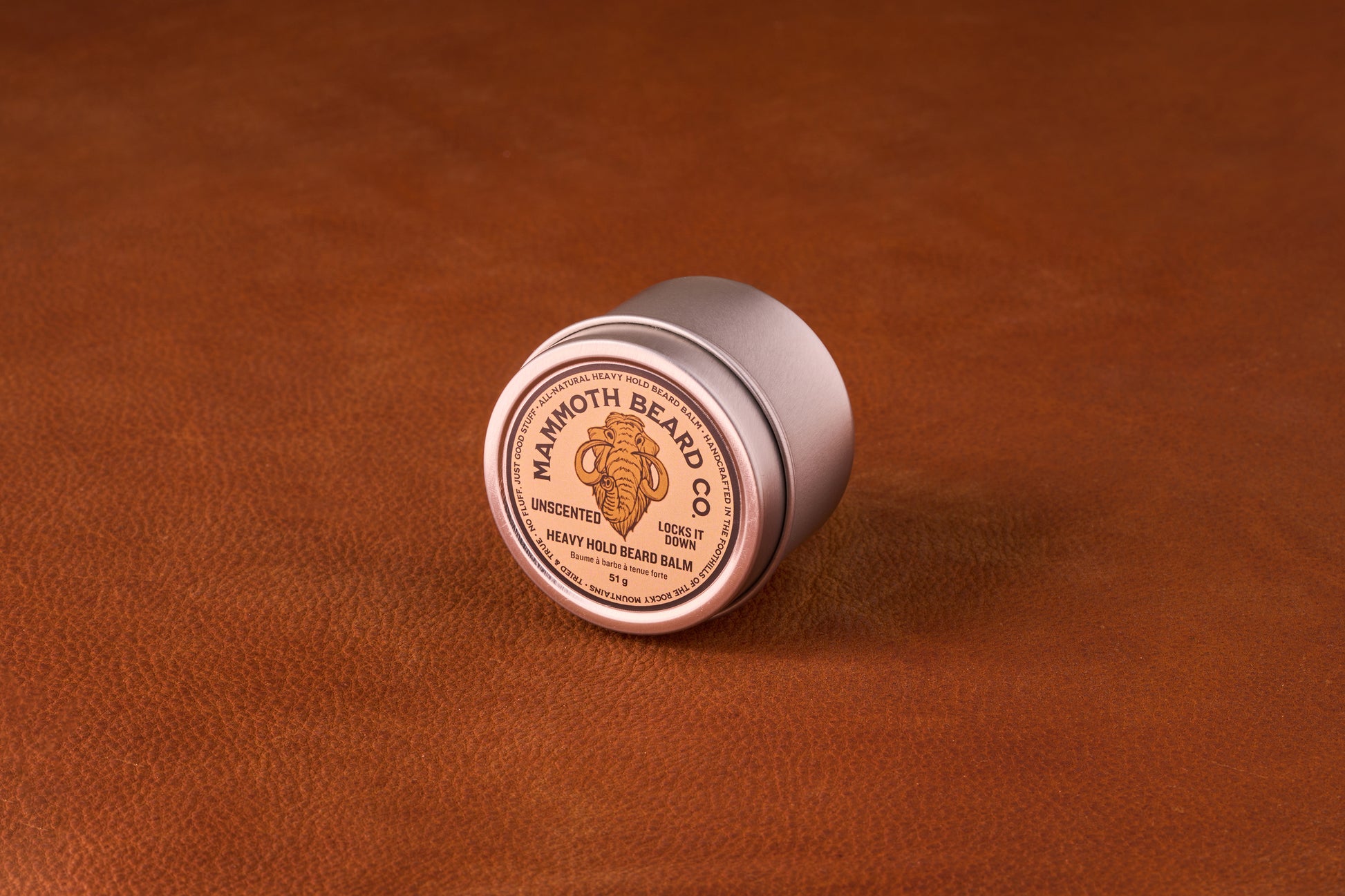Mammoth Beard Co. Strong Hold Beard Balm Unscented 60ml tin on leather, showcasing premium natural ingredients for styling and moisturizing beards.