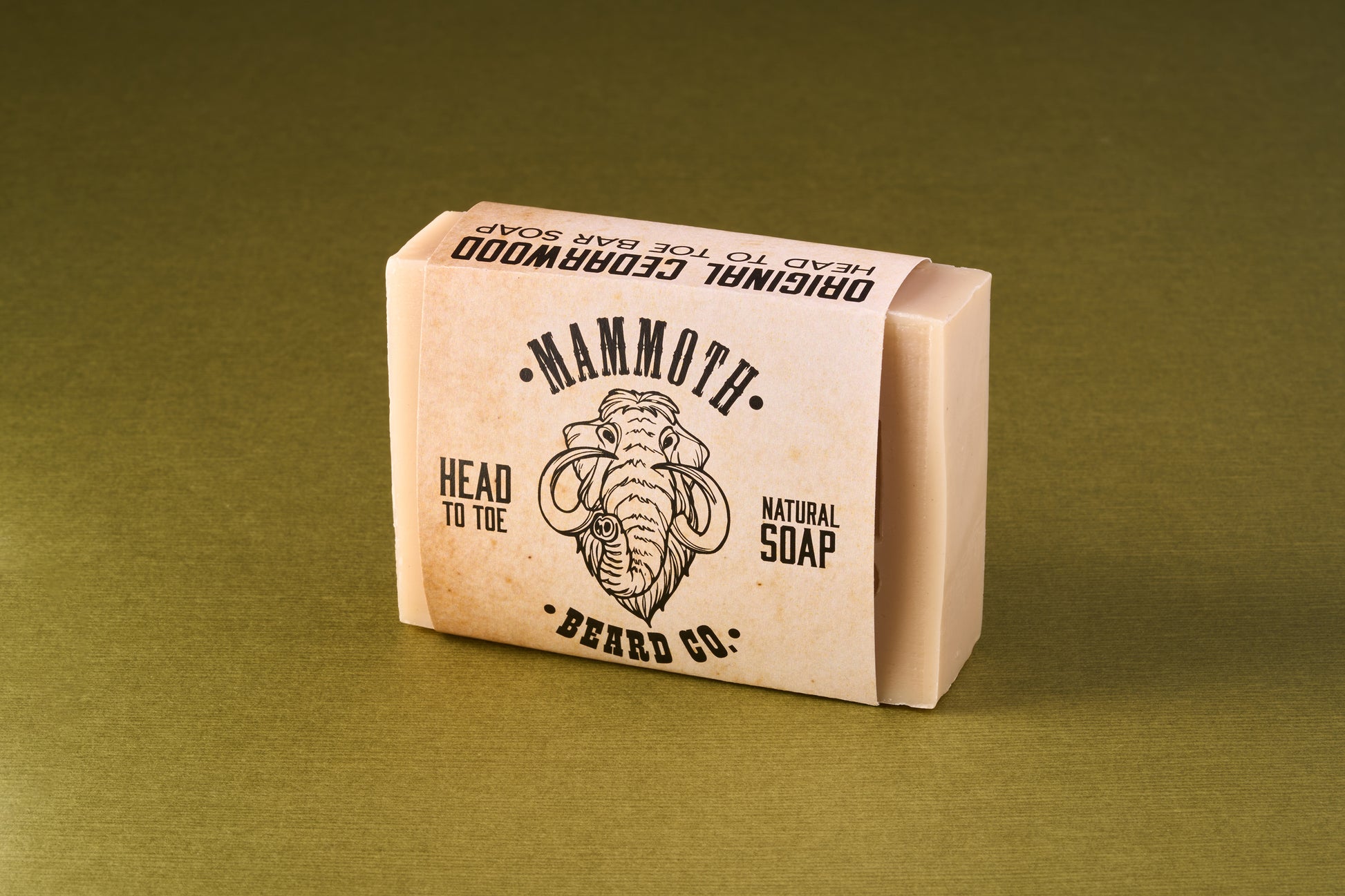 Mammoth Beard Co. Original Cedarwood Beard Soap wrapped in labeled paper band, featuring a stylized mammoth head illustration, ideal for gentle full-body and beard cleansing.