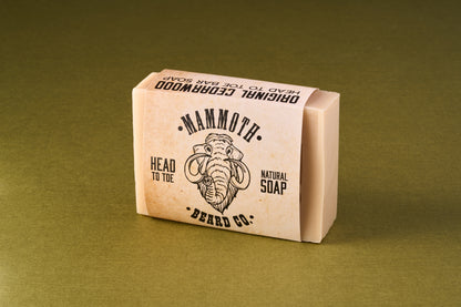 Mammoth Beard Co. Original Cedarwood Beard Soap wrapped in labeled paper band, featuring a stylized mammoth head illustration, ideal for gentle full-body and beard cleansing.