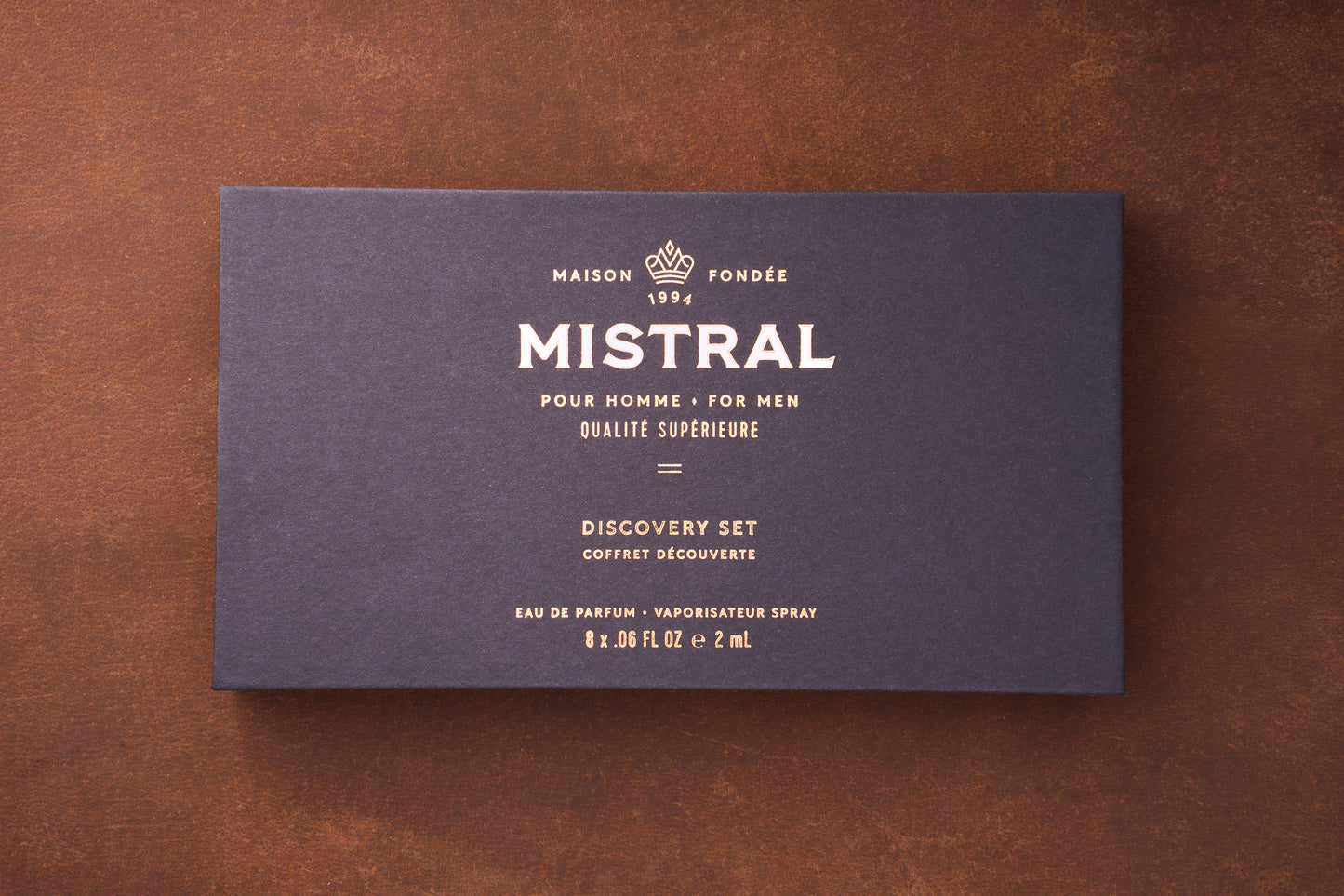 A dark blue box with gold text displays: MAISON FONDÉE 1994 MISTRAL POUR HOMME MEN'S COLOGNE QUALITÉ SUPÉRIEURE Mistral Eau de Parfum Discovery Set VAPORISATEUR SPRAY 8 x .06 FL OZ e 2 mL.