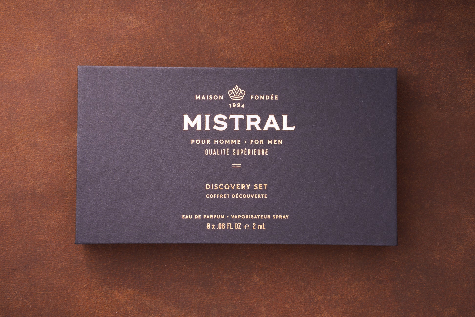 A dark blue box with gold text displays: MAISON FONDÉE 1994 MISTRAL POUR HOMME MEN'S COLOGNE QUALITÉ SUPÉRIEURE Mistral Eau de Parfum Discovery Set VAPORISATEUR SPRAY 8 x .06 FL OZ e 2 mL.